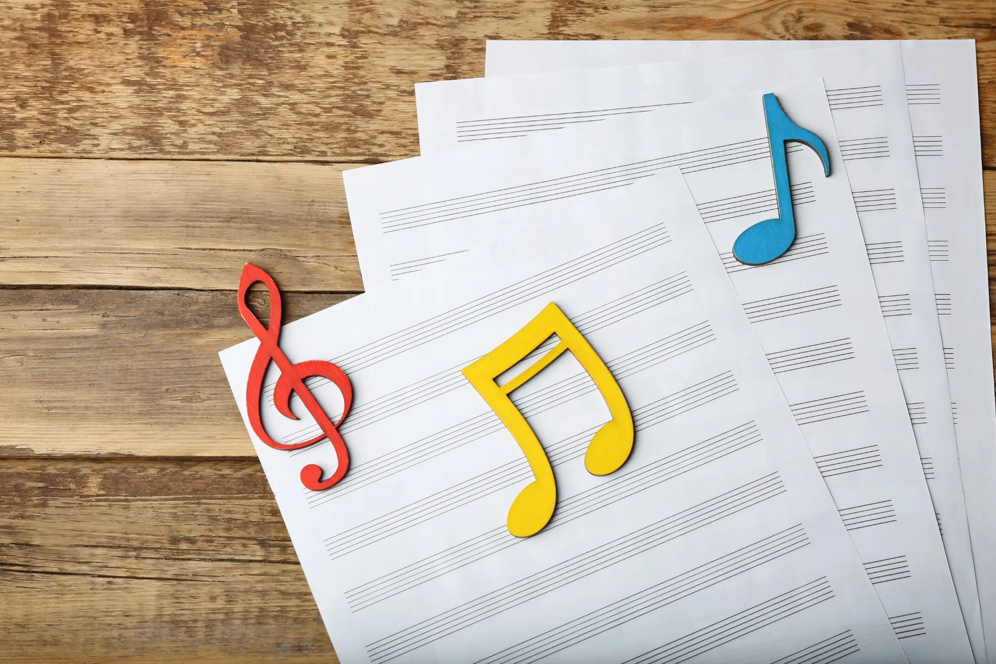 Colorful music notes on sheet music over a wooden background